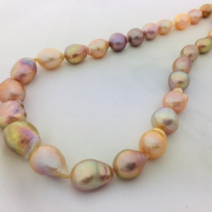 May include: A necklace made of large, baroque-shaped pearls in shades of pink, peach, and gold.