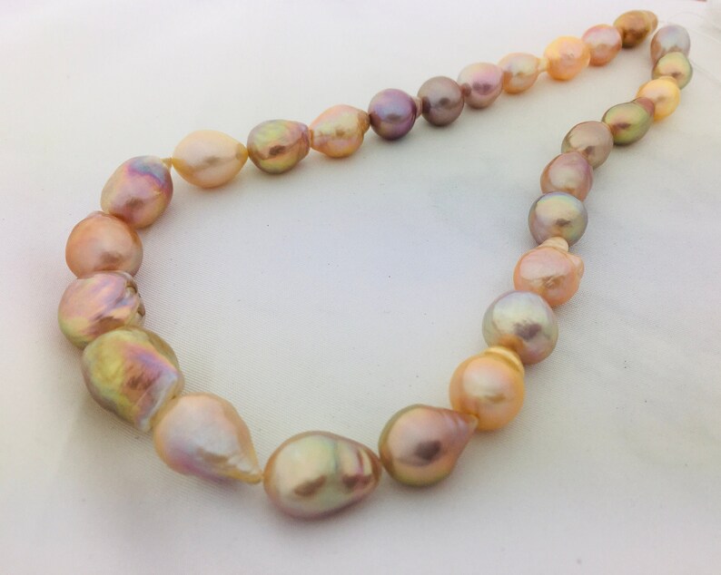 May include: A necklace made of large, baroque-shaped pearls in shades of pink, peach, and gold.