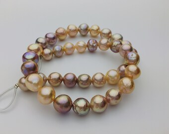 May include: A strand of iridescent pearls in shades of pink and gold. The pearls are strung on a clear cord and are approximately 10mm in diameter.