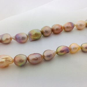 May include: A strand of baroque pearls in shades of pink, gold, and purple. The pearls are irregular in shape and have a lustrous sheen.