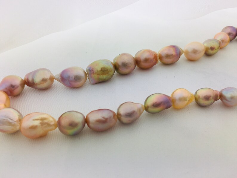 May include: A strand of baroque pearls in shades of pink, gold, and purple. The pearls are irregular in shape and have a lustrous sheen.
