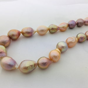 May include: A necklace made of large, baroque pearls in shades of pink, gold, and purple.