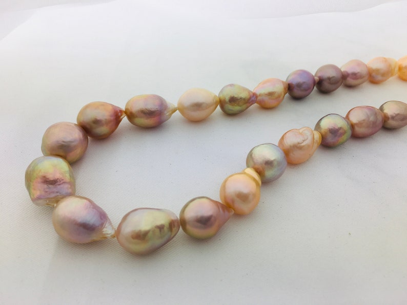 May include: A necklace made of large, baroque pearls in shades of pink, gold, and purple.