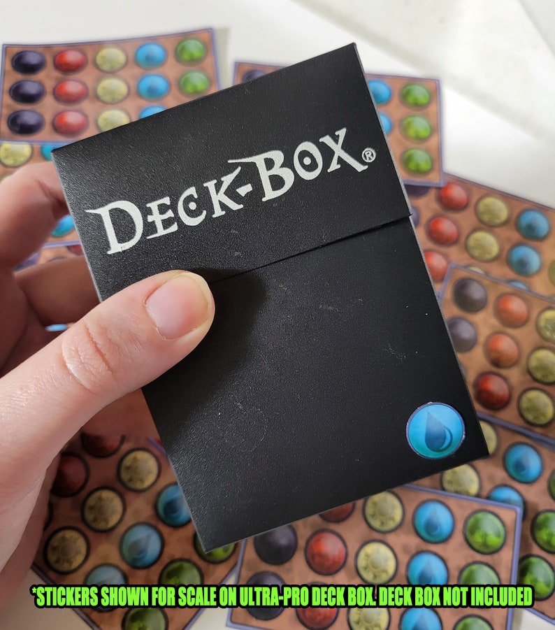 May include: A black DECK-BOX card box with a blue water drop sticker on the front. The text "STICKERS SHOWN FOR SCALE ON ULTRA-PRO DECK BOX. DECK BOX NOT INCLUDED" is printed below the box.