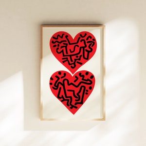 以下が含まれることがあります： 2つの赤いハートが黒色の抽象的なデザインで描かれた額装されたプリント。ハートは互いに重ねられています。