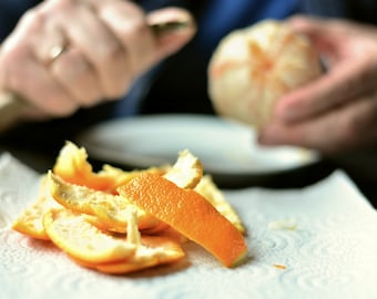 May include: A close-up of orange peels on a white paper towel. The peels are a bright orange color and are arranged in a pile.