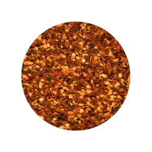 Puede incluir: Primer plano de copos de pimiento rojo, un chile seco y triturado, utilizado como especia en la cocina.