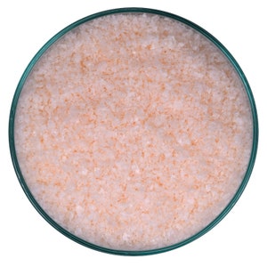 May include: A close-up view of a glass bowl filled with fine, pink Himalayan salt crystals.