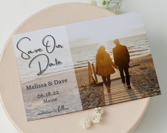 Könnte beinhalten: Save-the-Date-Karte mit einem Foto eines Paares, das auf einem Holzsteg in Richtung Meer geht. Der Text lautet "Save Our Date", "Melissa & Dave", "06.18.22", "Maine" und "invitation to follow".