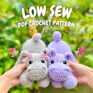 Op de afbeelding: Twee gehaakte nijlpaardspeeltjes, één grijs met een roze strik en één paars, worden omhoog gehouden tegen een wazige groene achtergrond. De tekst "LOW SEW PDF CROCHET PATTERN" wordt bovenaan de afbeelding weergegeven.