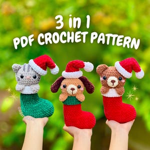 Könnte beinhalten: Drei gehäkelte Weihnachtsstrumpf-Ornamente, jedes mit einem anderen Tier: eine graue Katze, ein brauner Hund und ein brauner Bär. Jedes Tier trägt einen roten Weihnachtsmannhut. Der Text "3 in 1 PDF CROCHET PATTERN" ist darüber angezeigt.