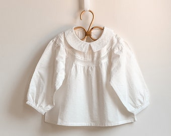 Reinweiße Baumwollbluse für Babys und Mädchen. Elegante Bluse für Mädchen. Shirts mit langen Ärmeln und Gummizug am Bündchen. Mädchen Kleidung