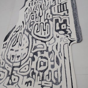 May include: Abstract black and white rug with a unique design. The rug has a textured surface and a fringed edge. The rug is made by RugResource.