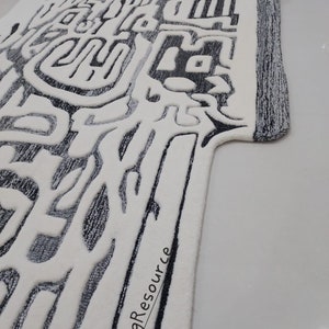 May include: A white and gray abstract patterned rug with a black border. The rug has a unique design with a textured surface. The text "RugResource" is printed on the rug.