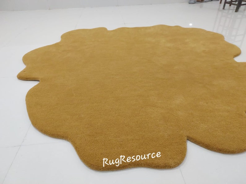 May include: A large, mustard yellow, cloud-shaped rug with a slightly irregular shape. The rug is made of a soft, plush material and has a subtle texture. The text "RugResource" is printed in white on the rug.