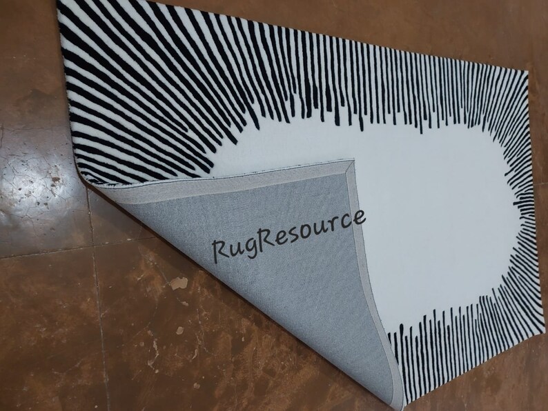 May include: Black and white striped rug with a large white circle in the center. The rug is folded in half, showing the gray backing. The text "RugResource" is visible on the backing.