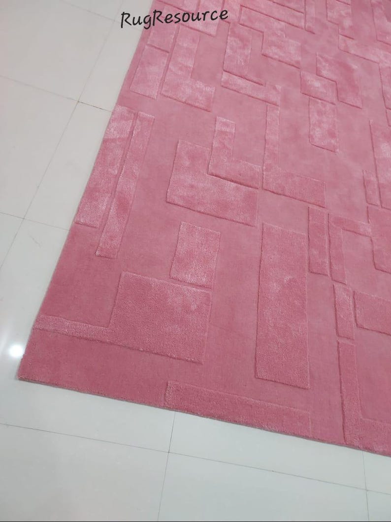 May include: A pink area rug with a geometric pattern. The rug has a raised, textured design.