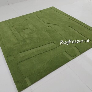 May include: A green shag rug with a geometric pattern. The rug has a raised design, creating a textured surface. The rug is made of soft, plush fibers.