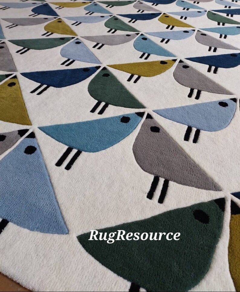 May include: A white rug with a geometric pattern of blue, green, gray, and yellow birds. The rug has a modern design and is perfect for a living room or bedroom.