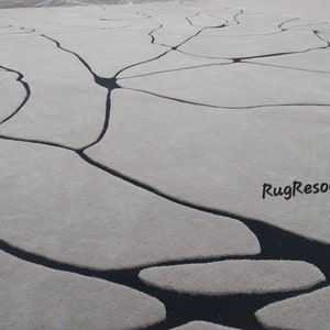 Puede incluir: Una alfombra blanca con un dise&ntilde;o abstracto negro. El dise&ntilde;o se asemeja a una red de venas o grietas. La alfombra tiene una textura suave y mullida. RugResource est&aacute; impreso en la esquina inferior derecha.