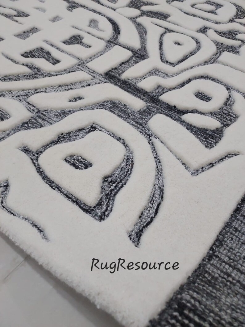 May include: White and gray area rug with a modern abstract design. The rug has a raised texture and a border of gray.