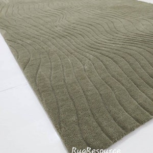 May include: A green area rug with a wavy, textured pattern. The rug is made of a soft, plush material.