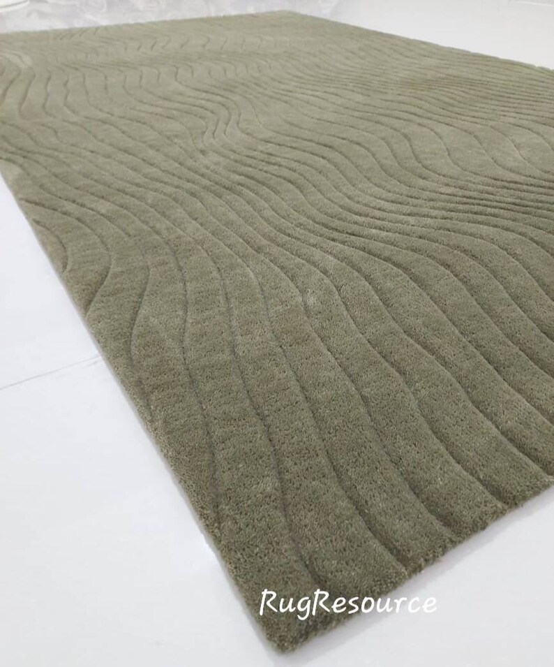 May include: A green area rug with a wavy, textured pattern. The rug is made of a soft, plush material.