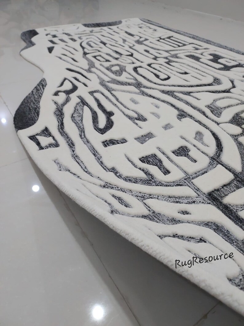 May include: A white and gray area rug with an abstract design. The rug has a thick, plush pile and a fringed edge.