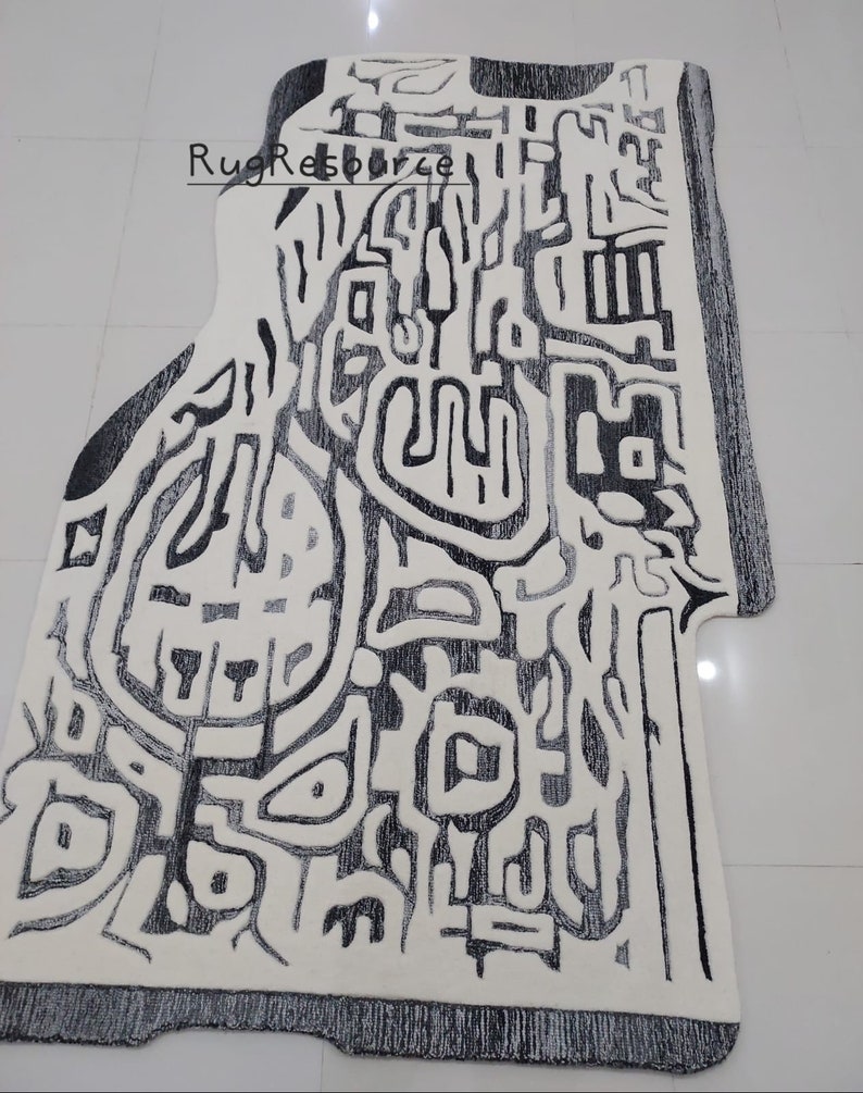 May include: Abstract black and white area rug with a geometric design. The rug has a unique shape and is made of a soft, plush material.