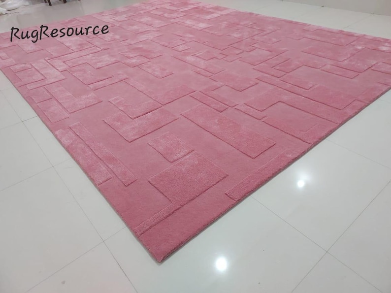 May include: A pink area rug with a geometric pattern. The rug has a raised texture and a soft, plush feel.