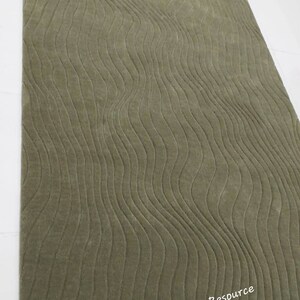 May include: A green shag rug with a wavy, textured pattern. The rug is made of soft, plush fibers and has a modern, contemporary design.