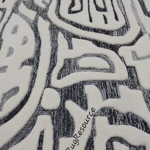 May include: Close-up of a white and gray rug with a textured, abstract design. The rug has a raised, 3D effect, creating a unique and modern look. The text "RugResource" is visible in the lower right corner of the image.