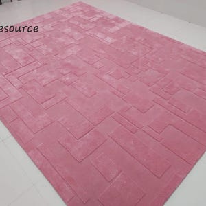 May include: A pink area rug with a geometric pattern. The rug has a soft, plush texture.
