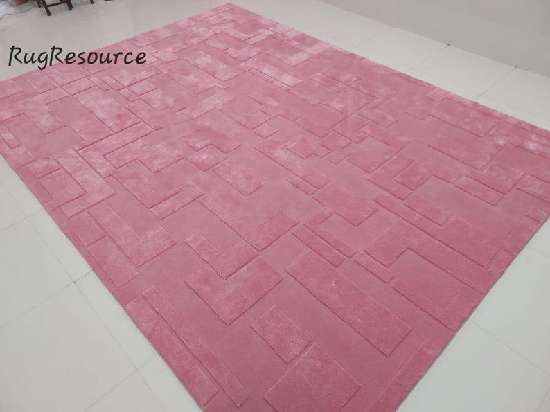 May include: A pink area rug with a geometric pattern. The rug has a soft, plush texture.