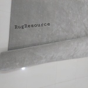 以下が含まれることがあります： 「RugResource」という文字が印刷された、巻かれた灰色の敷物です。
