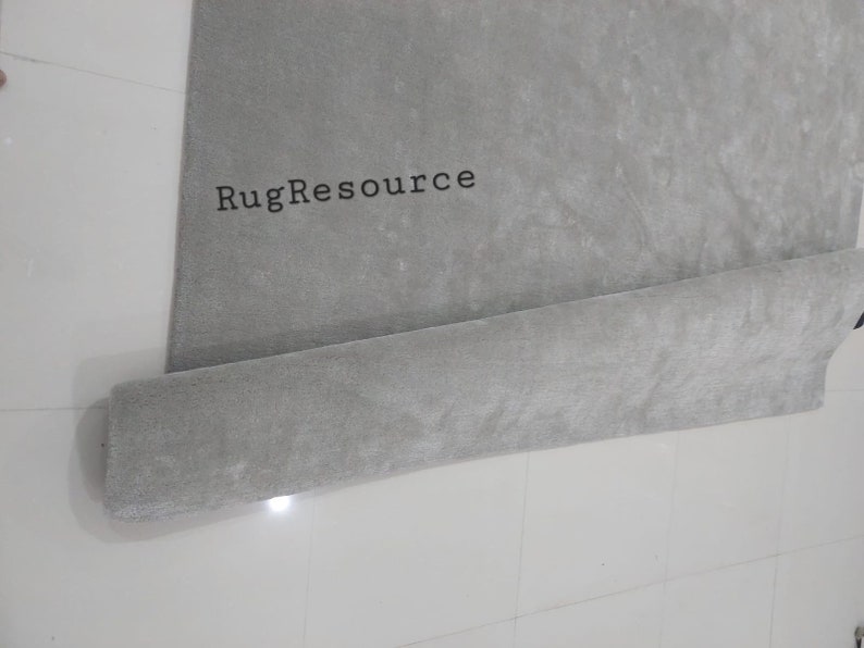 以下が含まれることがあります： 「RugResource」という文字が印刷された、巻かれた灰色の敷物です。