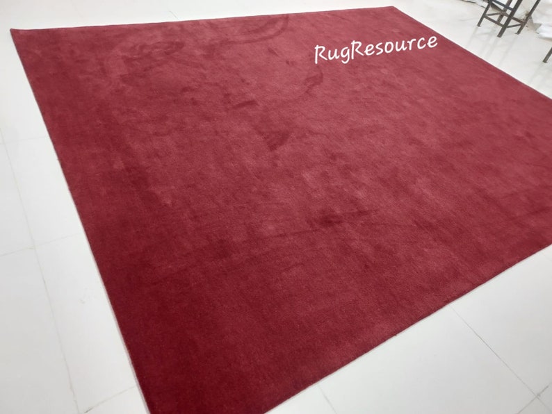 May include: A solid red rug with a soft, plush texture. The rug is laid out flat on a white tiled floor. The text "RugResource" is visible in the upper right corner of the rug.