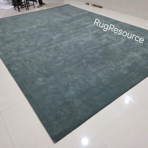 K&ouml;nnte beinhalten: Ein gro&szlig;er, rechteckiger, teal-farbener Teppich. Der Teppich hat ein weiches, strukturiertes Aussehen und liegt auf einem gefliesten Boden. Die Worte "RugResource" sind in der oberen rechten Ecke sichtbar.
