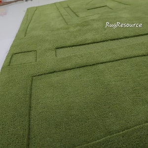 May include: A green shag rug with a geometric pattern. The rug has a raised design that creates a textured surface.