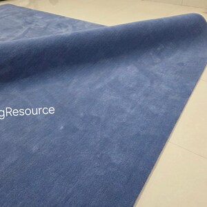 May include: A rolled-up, solid blue rug with a soft, textured surface. The rug is displayed on a light-colored tiled floor. The text "RugResource" is visible in the lower left corner.