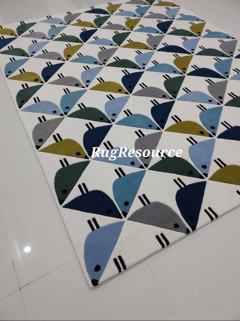 May include: A white rug with a geometric pattern of blue, green, and yellow birds. The rug has a modern design and is perfect for a child's room or play area.