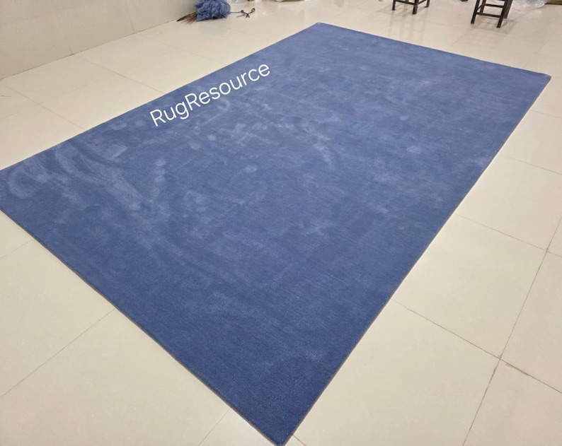 May include: A large, rectangular blue rug with a textured surface. The rug is placed on a tiled floor. The text "RugResource" is visible in the upper left corner. This rug is suitable for living rooms, bedrooms, or other spaces.