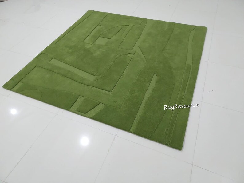 May include: A green wool rug with a geometric pattern. The rug has a raised texture and is made of high-quality materials.