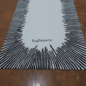 May include: A white oval rug with a black and white striped border. The stripes are arranged in a radial pattern, creating a sunburst effect. The rug has the text "RugResource" in the center.