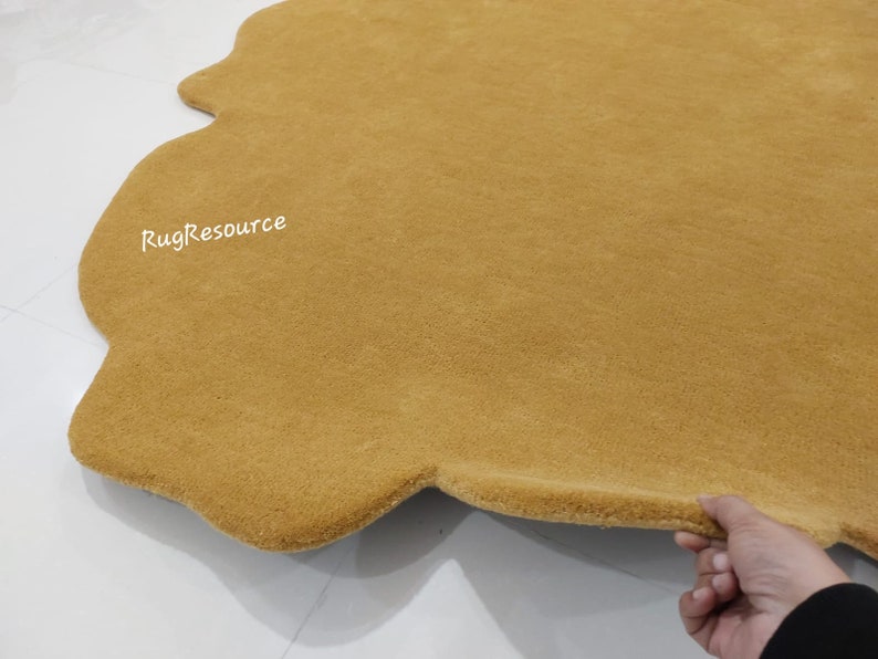 May include: A mustard yellow, fluffy, cloud-shaped rug with a slightly irregular shape. The rug is made of a soft, plush material and has a subtle sheen. The text "RugResource" is visible in the upper left corner of the rug.