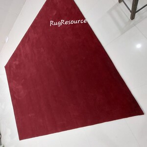 May include: A large, triangular, burgundy-colored rug with the text "RugResource" printed in white in the center.