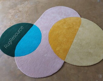 May include: A colorful abstract rug with a green, blue, yellow, and pink design. The rug is made of soft, plush material and features a unique, modern style.
