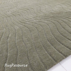 May include: A green area rug with a wavy pattern. The rug is made of a soft, plush material and has a subtle sheen. The rug is shown in a close-up view, with the texture of the fabric clearly visible. The text "RugResource" is visible in the lower left corner of the image.