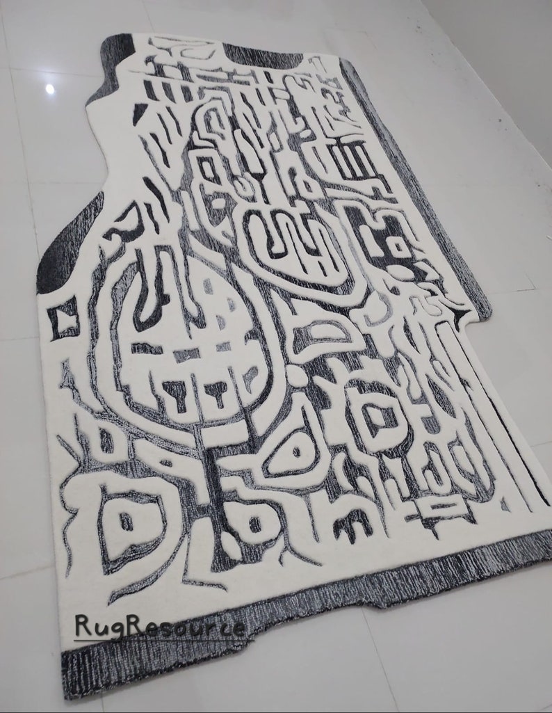 May include: A white and black abstract rug with a unique design. The rug has a fringe border and the text "RugResource" is printed on the bottom right corner.