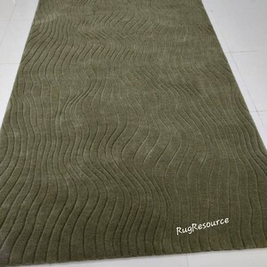 May include: A green area rug with a wavy, textured pattern. The rug has a subtle sheen and is made of a soft, plush material. The text "RugResource" is visible in the bottom right corner of the rug.